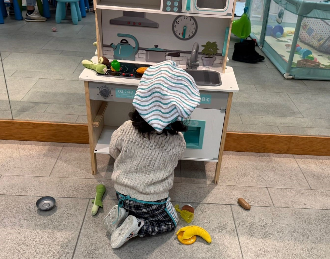 Niña jugando con cocina y alimentos de juguete