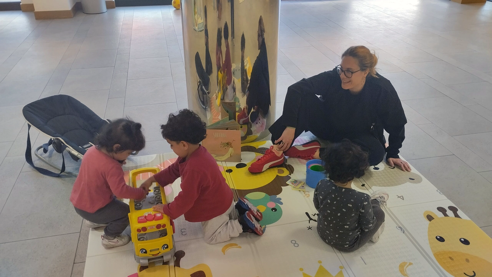 Niños pequeños jugando con profesional acompañándoles